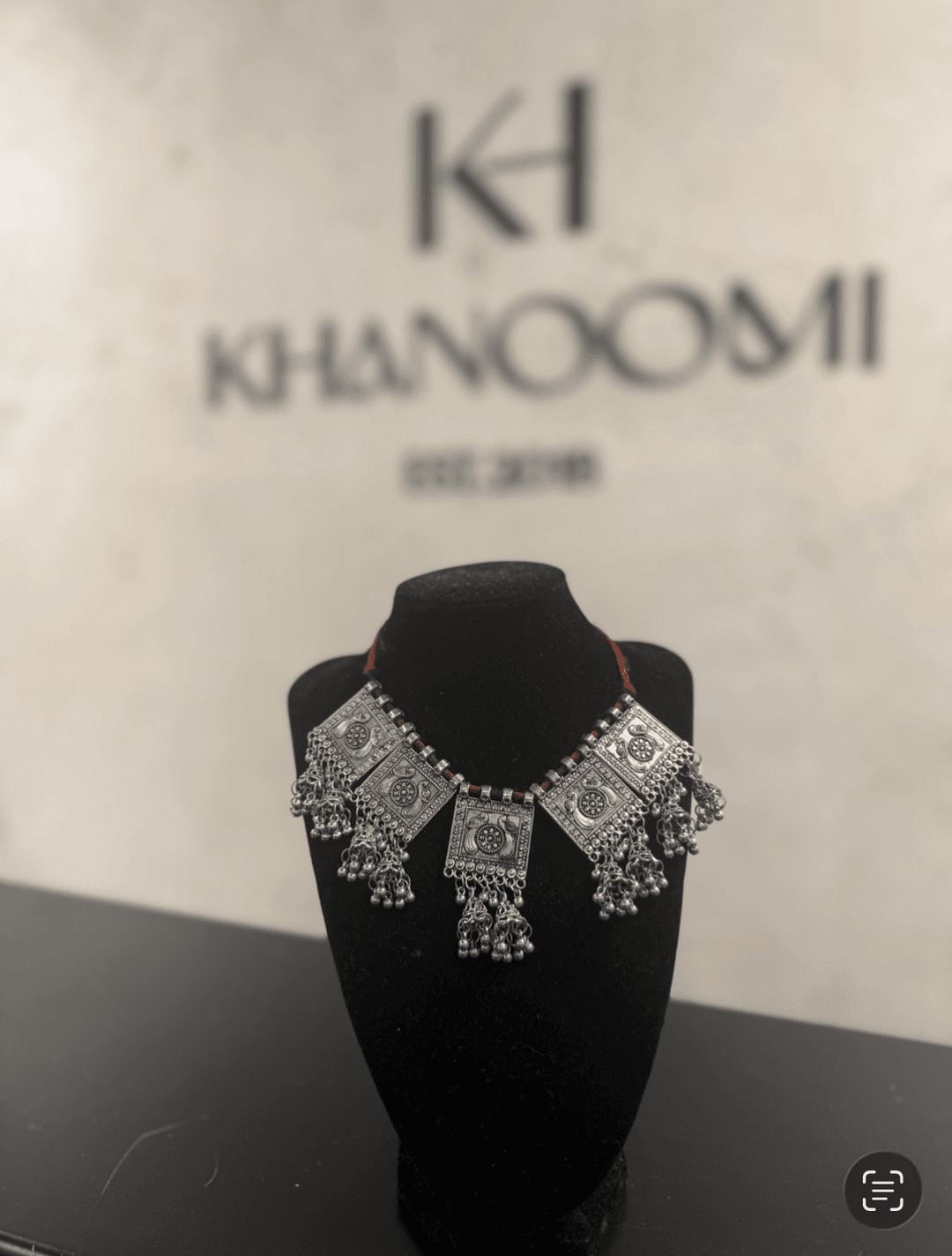 Authentic Afghan antique silver necklace with hand-engraved panels and cascading bells on a black jewelry bust.